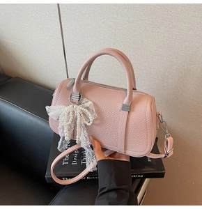 Close-up of pink pebble faux leather bowling bag with lace pearl bow charm detail