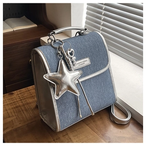 Close-up of blue denim shoulder bag with silver leather trim and star pendant