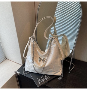 Détail du sac hobo blanc avec motif papillon, chaîne argentée et sangle de perles
