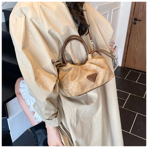 Close-up of pleated khaki shoulder bag with vintage leather handle and logo detail