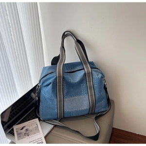 Detail of a large denim tote bag featuring patchwork stitching and striped handles