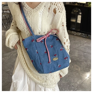 Close-up of cherry embroidery and red plaid bow on the denim canvas tote bag