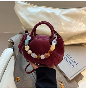 Détail du sac seau plissé en velours bordeaux avec des perles colorées décoratives