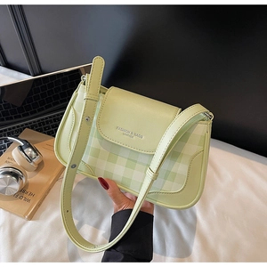 Detail of light green checkered crossbody bag with adjustable strap in a daily life setting