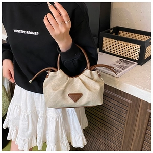 Detail of canvas tote bag showing brown leather trim and triangle logo plaque decoration