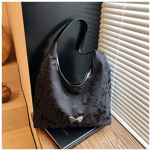 Detailansicht einer schwarzen Schultertasche mit Schmetterlingsmuster und Metallschnalle