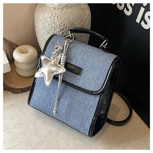 Detail of blue denim shoulder bag with black leather trim and silver star pendant