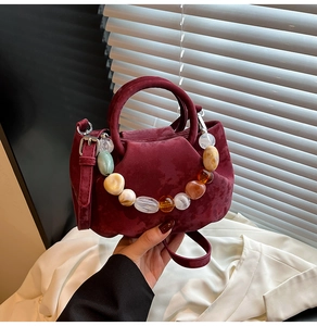Détail d'un sac seau en daim bordeaux avec perles en résine colorées en décor de vie