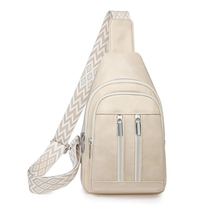 Detail view of cream crossbody bag featuring multiple zippers and a geometric patterned strap
