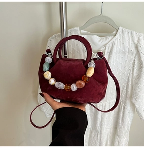 Vue détaillée du sac seau bordeaux en daim avec poignée décorative en grosses perles
