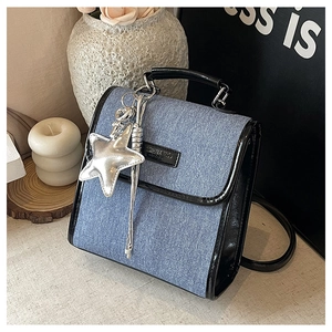 Detail of light blue denim shoulder bag with black patent leather trim and star charm