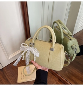 Green leather pillow bag with white lace bow and pearl pendant shown in a mirror reflection