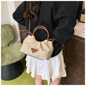 Close-up of pleated beige canvas bag with brown round handles and triangular logo detail