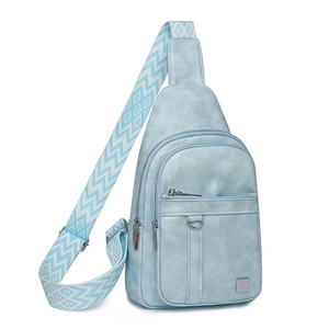 Detail of light blue crossbody bag with geometric strap and silver hardware accents