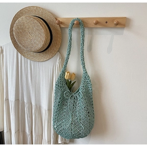 Detail of mint green hollow crochet tote bag hanging with summer vacation accessories