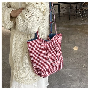 Detail of red gingham tote bag featuring a bow tie and stylish cursive typography print
