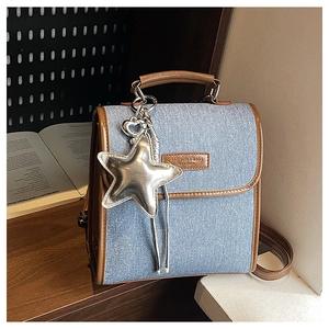 Close-up of retro denim handbag with brown leather trim and silver star pendant detail