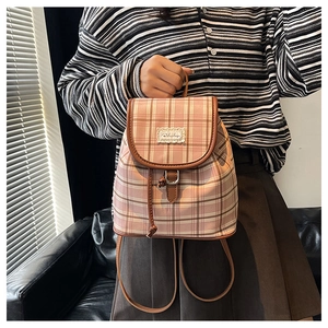 Detailed close-up of pink checkered canvas backpack with leather trim and lace accents