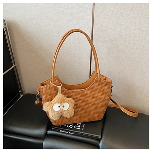 Détail d'un sac cabas tressé marron en demi-lune avec breloque étoile et bandoulière
