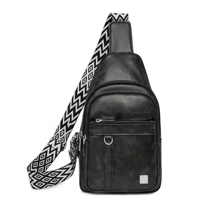 Close-up of black leather crossbody bag featuring geometric patterned wide shoulder strap