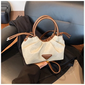 Detail of pleated beige canvas handbag with brown leather trim and triangle logo
