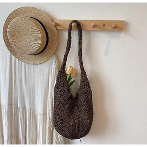 Detail of dark brown crochet tote bag with hollow knit pattern on wooden hanger