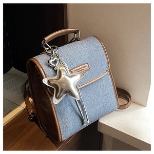Detailed view of denim shoulder bag featuring brown leather trim and star pendant