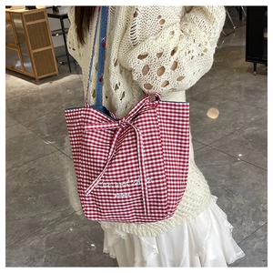 Detail of red checkered canvas tote bag with a decorative bow and printed slogan