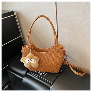 Gros plan sur un sac cabas tressé caramel avec breloque étoile et texture riche