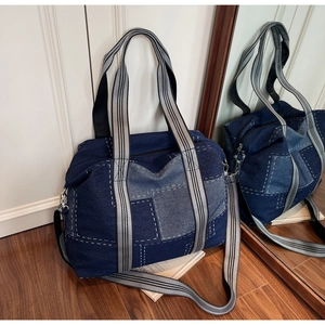 Detail of multi-tone denim patchwork tote with striped straps and adjustable shoulder strap