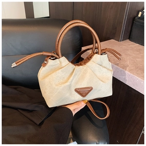 Detail of beige canvas pleated bag with brown leather handles and brand triangle logo