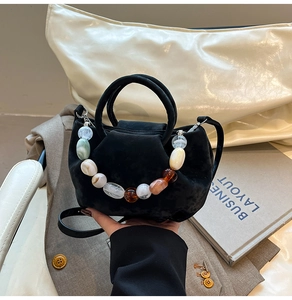 Détail du sac seau en suède noir avec chaîne en perles de résine et anse ronde