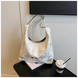 Detail der silbernen Schmetterlingsschnalle an der weißen Hobo-Bag mit Paillettenmuster