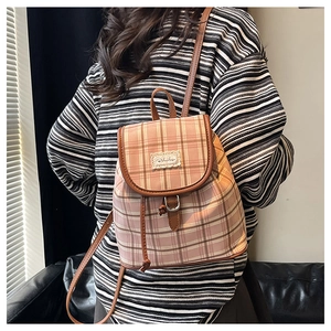 Detail view of retro plaid canvas backpack with leather trim and drawstring closure