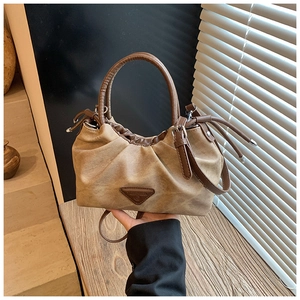 Close-up of pleated khaki suede handbag featuring a brown triangle logo and retro design