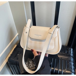 Detail of cream leather baguette bag with checkered pattern and magnetic flap closure