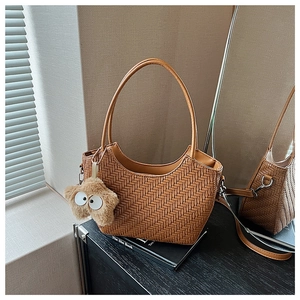Détail d'un sac cabas tressé marron avec anse ronde et charm étoile en peluche