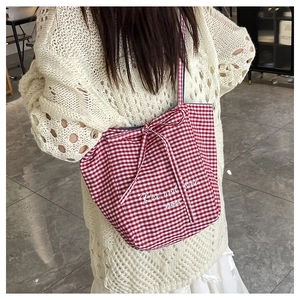 Close-up detail of red gingham tote bag with bow tie straps and Rise and Shine print