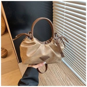 Detail of camel ruched handbag with brown leather handle and metal triangle logo