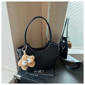 Détail du sac fourre-tout tissé noir avec porte-clés peluche étoile jaune sur la table