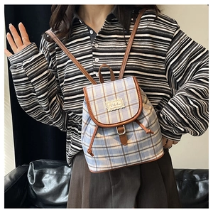 Detail of light blue plaid canvas mini backpack with leather straps and drawstring closure