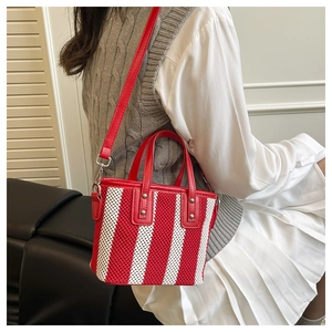 Détail d'un mini cabas tissé à rayures rouges et blanches avec anses en cuir et rivets