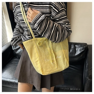 Close-up of yellow checkered canvas tote bag featuring Rise and Shine artistic lettering