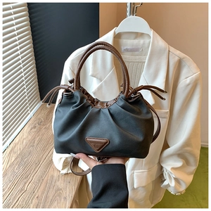 Detail of ruched black dumpling bag featuring brown handles and triangle brand plaque