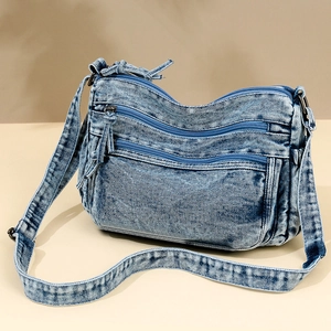 Blue washed denim crossbody bag with multiple zipper compartments and adjustable strap