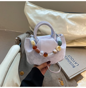 Détail du sac seau plissé lilas avec des perles multicolores décoratives sur l'anse