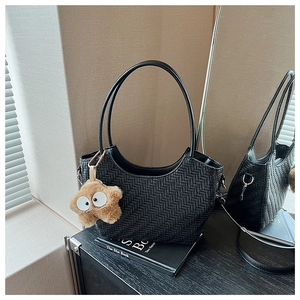 Détail du sac tissé noir avec un porte-clés étoile en peluche marron et bandoulières