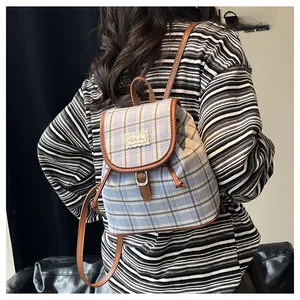 Detail of blue and white checkered canvas backpack with brown leather trim and lace patch