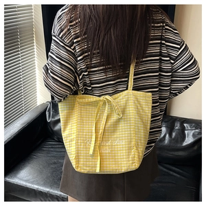 Detail of yellow gingham tote bag featuring bow tie strap and Rise and Shine print