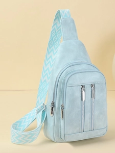 Light blue crossbody chest bag with woven geometric strap on warm beige background